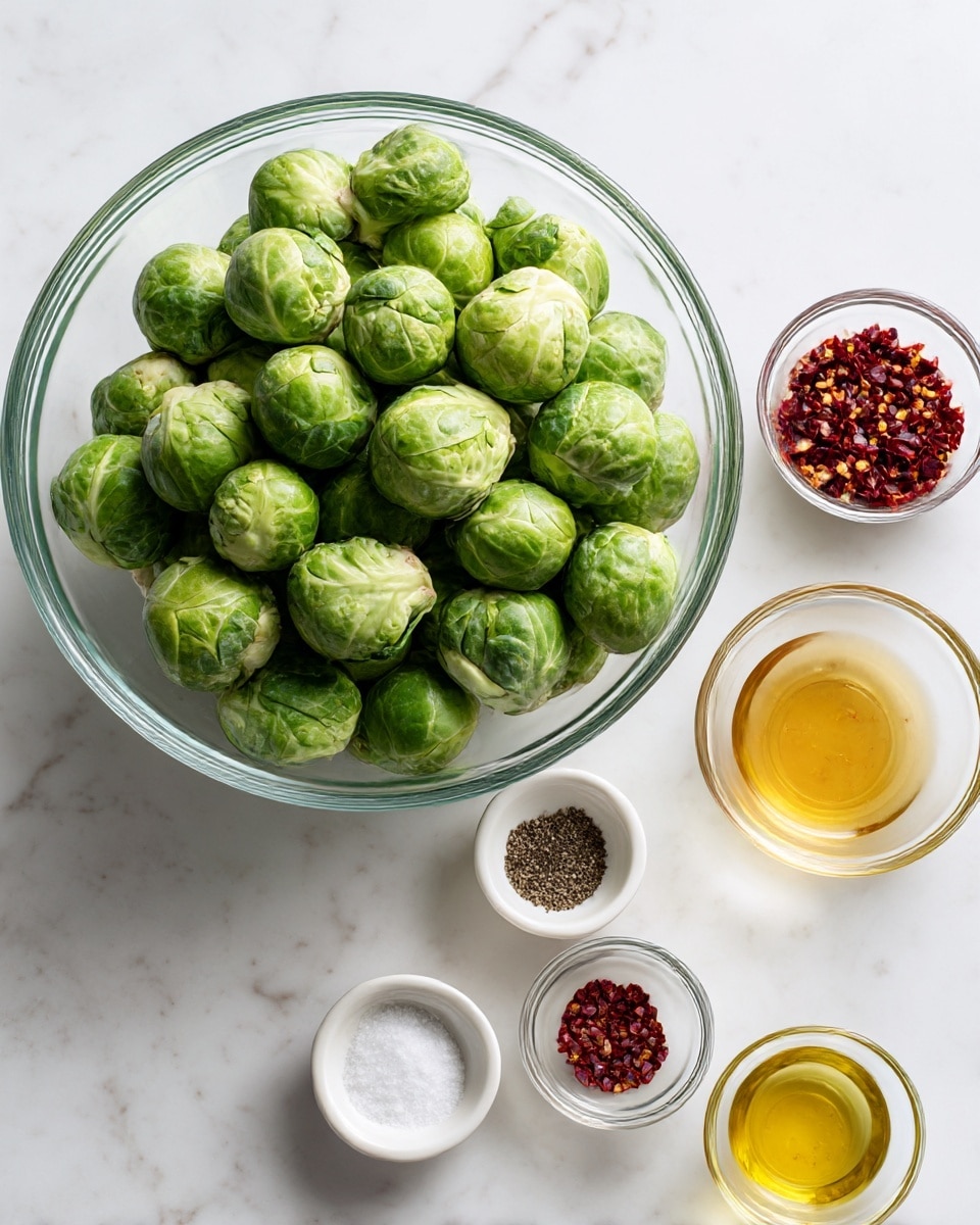 A clear glass bowl filled with whole green Brussels sprouts sits in the top left on a white marbled surface. To the right of the bowl is a small clear bowl with red chili flakes. Below them, there are four small bowls arranged loosely: one white bowl with black pepper, one white bowl with salt, one small clear bowl filled with golden liquid (likely honey), and one small clear bowl containing yellowish oil. The scene looks neat and organized with the bowls showing a variety of colors like green, yellow, red, and black. photo taken with an iphone --ar 4:5 --v 7