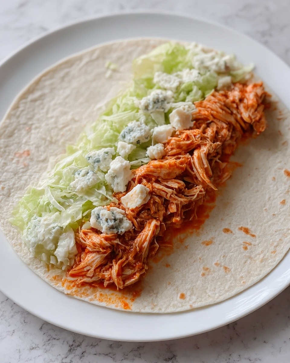 A white tortilla lies flat on a white plate with a white marbled surface beneath. On the tortilla, there is a bottom layer of shredded chicken mixed with a reddish-orange sauce, giving it a moist and textured look. Alongside the chicken, there is a layer of light green shredded lettuce, adding a fresh, crisp texture. On top of the chicken, there are scattered chunks of white cheese with blue mold spots, adding contrast and visual interest. The layers are neatly placed in a line across the center of the tortilla. photo taken with an iphone --ar 4:5 --v 7
