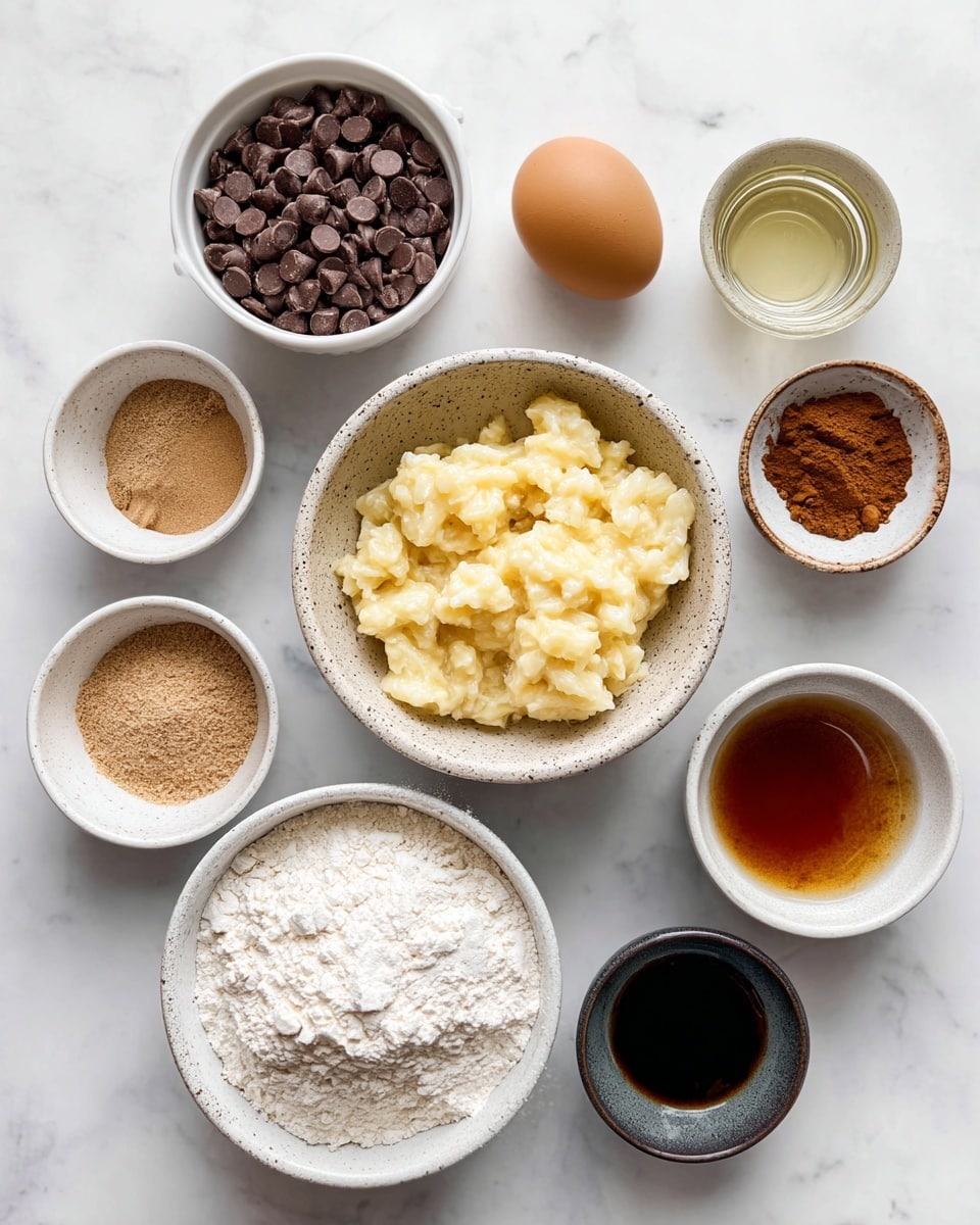 The image shows various ingredients for baking arranged neatly on a white marbled surface. At the top left, a 1-cup white measuring cup is filled with dark brown chocolate chips, next to a small white bowl holding a light brown egg. Below, a speckled white bowl is filled with mashed banana that is light yellow with soft texture. To the right, there is a dark gray small bowl with clear oil, and below it, a small white bowl with dark brown vanilla extract. A white measuring cup holds amber maple syrup near the right edge. At the bottom center, a white bowl contains a mix of dry ingredients: white flour, white protein powder, white baking powder, light beige cornstarch, light brown baking soda, a pinch of salt, and cinnamon and nutmeg in warm brown hues, all layered in separate piles within the bowl. photo taken with an iphone --ar 4:5 --v 7