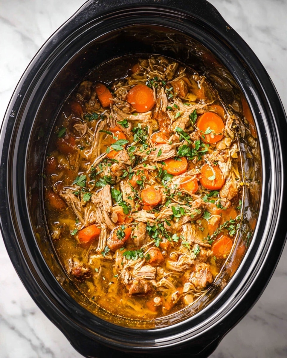 Inside a shiny black slow cooker, there is a stew with mainly two layers. The bottom layer is a thick golden brown broth that looks warm and slightly oily. On top, there are many small, shredded pieces of light brown cooked meat mixed with bright orange carrot slices scattered all over. Small bits of fresh green herbs are sprinkled across the stew, adding a touch of color. The slow cooker sits on a white marbled surface. Photo taken with an iphone --ar 4:5 --v 7