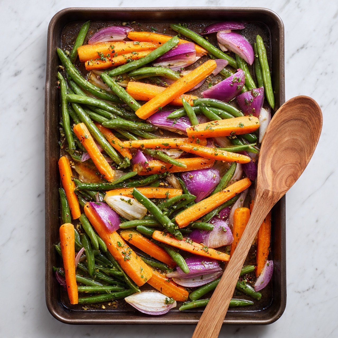 A baking tray filled with colorful raw vegetables, including bright orange carrot sticks, green beans, and sliced purple onion wedges scattered evenly across the tray. The vegetables are lightly coated with herbs and small bits of garlic, giving a fresh and slightly glossy look. A wooden spoon rests diagonally on the lower right side of the tray, touching the vegetables. The tray sits on a white marbled surface, highlighting the vibrant colors and textures of the vegetables photo taken with an iphone --ar 4:5 --v 7