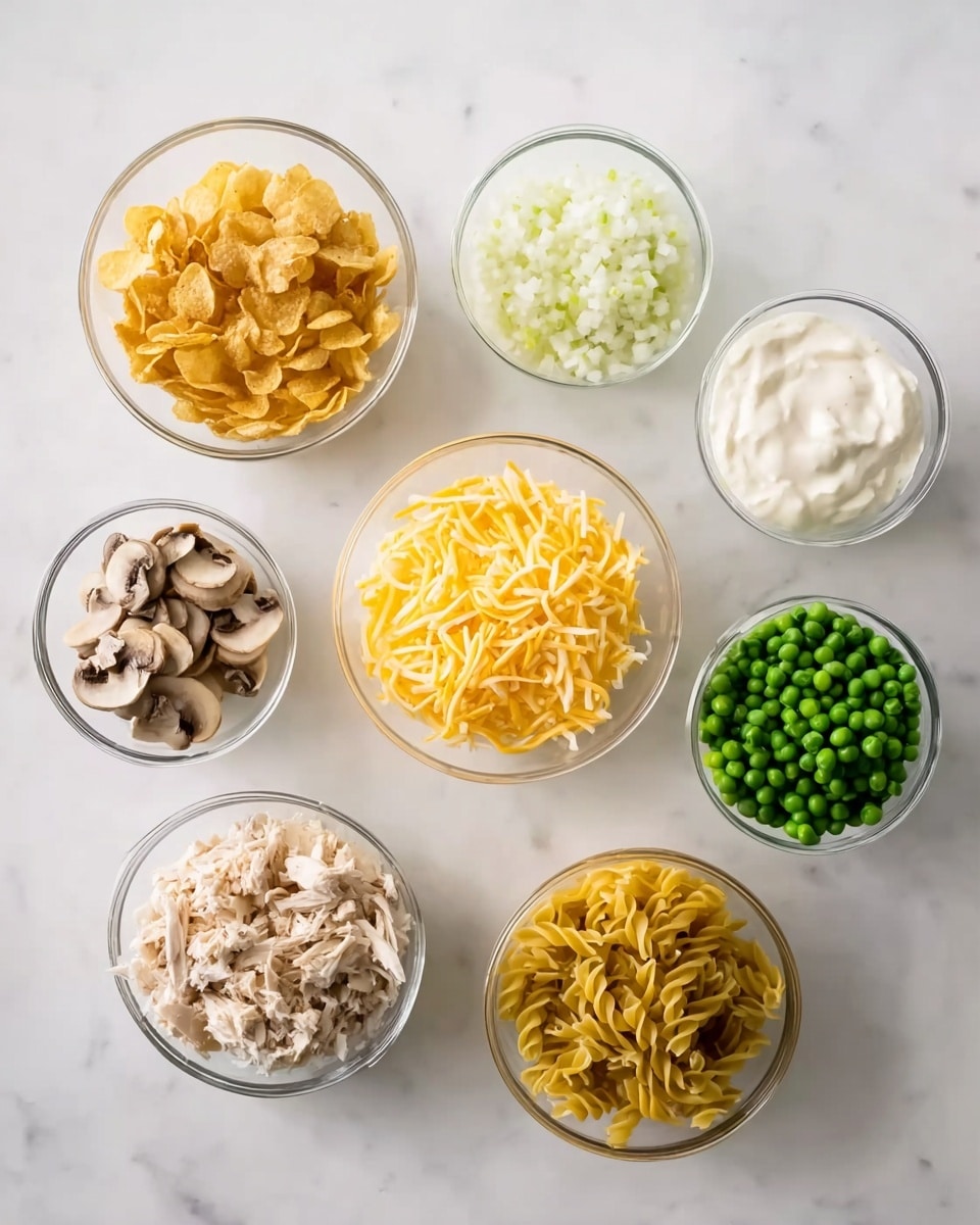 The image shows eight small white bowls arranged on a white marbled surface, each holding different ingredients. Starting from the top left, there is a bowl filled with crushed potato chips, next to it is a bowl of chopped white onions to the right. Below the potato chips, there is creamy ranch sauce in a bowl, followed by a bowl of shredded yellow cheddar cheese in the center. To the right of the cheese, there is a bowl with green peas. On the bottom left, a bowl contains sliced mushrooms, next to it is a bowl with shredded chicken, and finally, on the bottom right, there is a bowl filled with uncooked yellow pasta noodles. All bowls are clear or white, showing the textures and colors of the ingredients clearly. The photo taken with an iphone --ar 4:5 --v 7