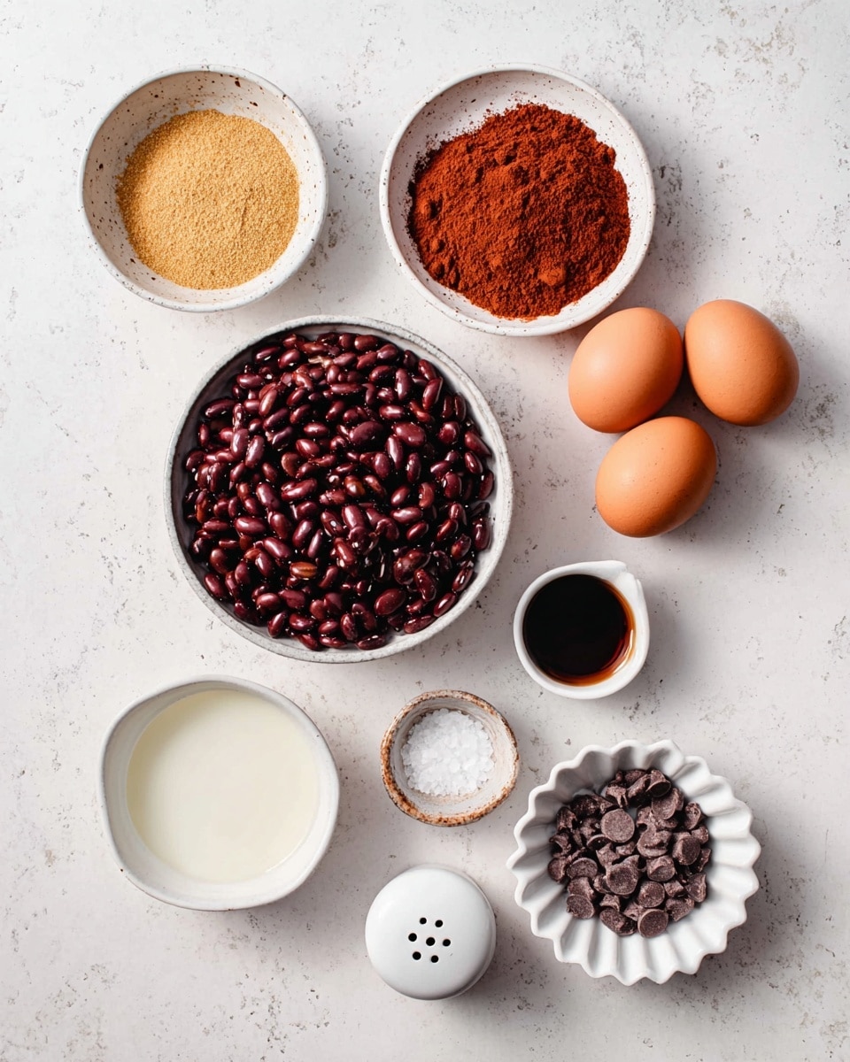 The image shows a top view of ingredients placed on a white marbled surface, arranged neatly in separate white bowls and plates. There are seven items: a bowl filled with dark red beans in the center, a bowl of light brown powder to the top left, and a bowl with reddish-brown powder to the top right. On the right side, three brown eggs sit directly on the surface next to a small white sauce dish containing a dark liquid. At the bottom right, white scalloped bowl holds small dark brown chocolate chips. Below the beans, there is a small white dish with a white creamy substance, and next to it is a small white salt shaker and a small round white dish with coarse salt. All items are organized clearly and evenly spaced. Photo taken with an iphone --ar 4:5 --v 7