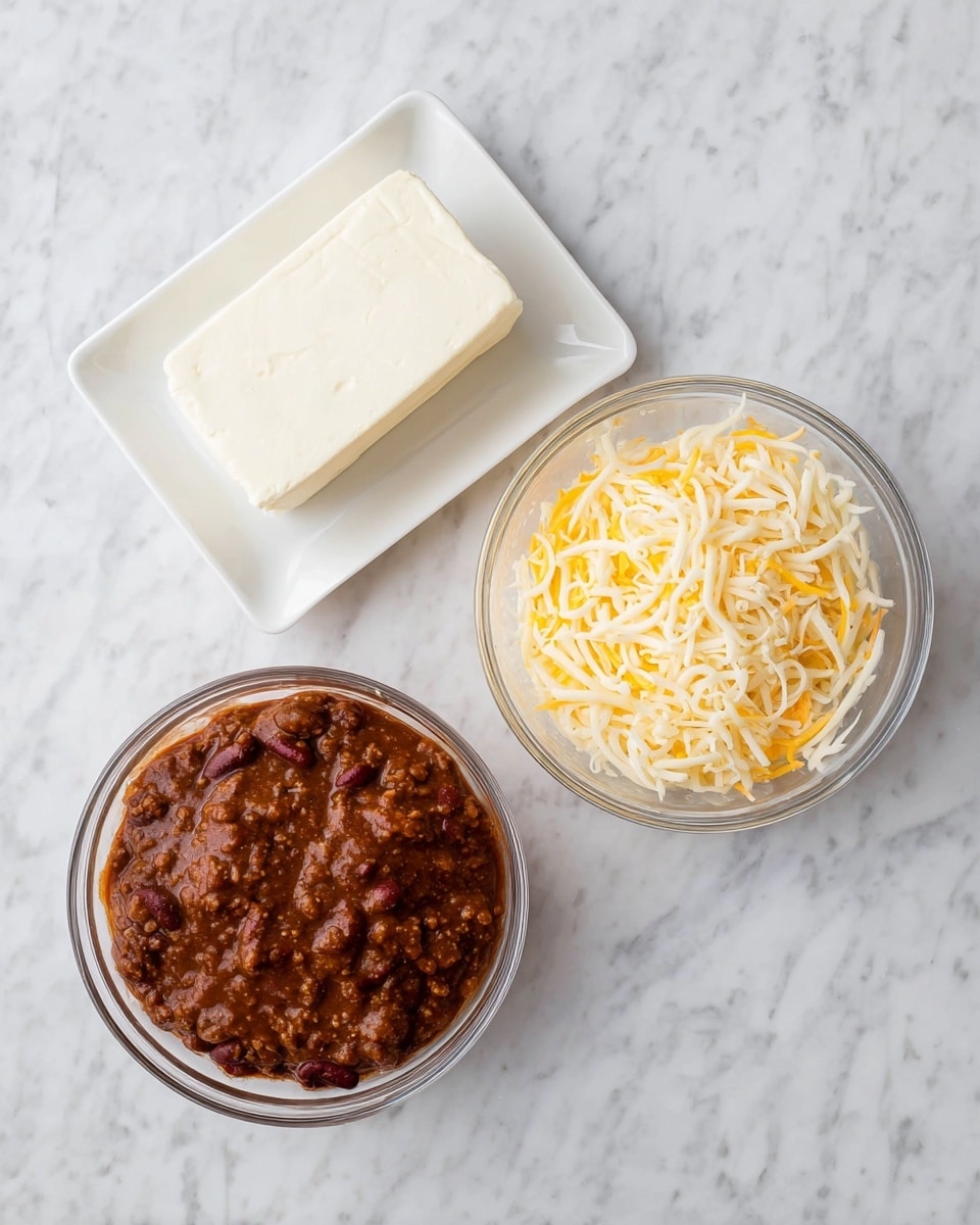 The image shows three separate elements on a white marbled surface: at the top left is a white rectangular plate with a smooth, solid block of white cream cheese; at the top right is a clear glass bowl filled with a mix of shredded yellow and white cheese, with fine strands loosely piled; and at the bottom is a larger clear glass bowl holding a thick, chunky brown chili with visible beans and meat, the surface glistening slightly. photo taken with an iphone --ar 4:5 --v 7