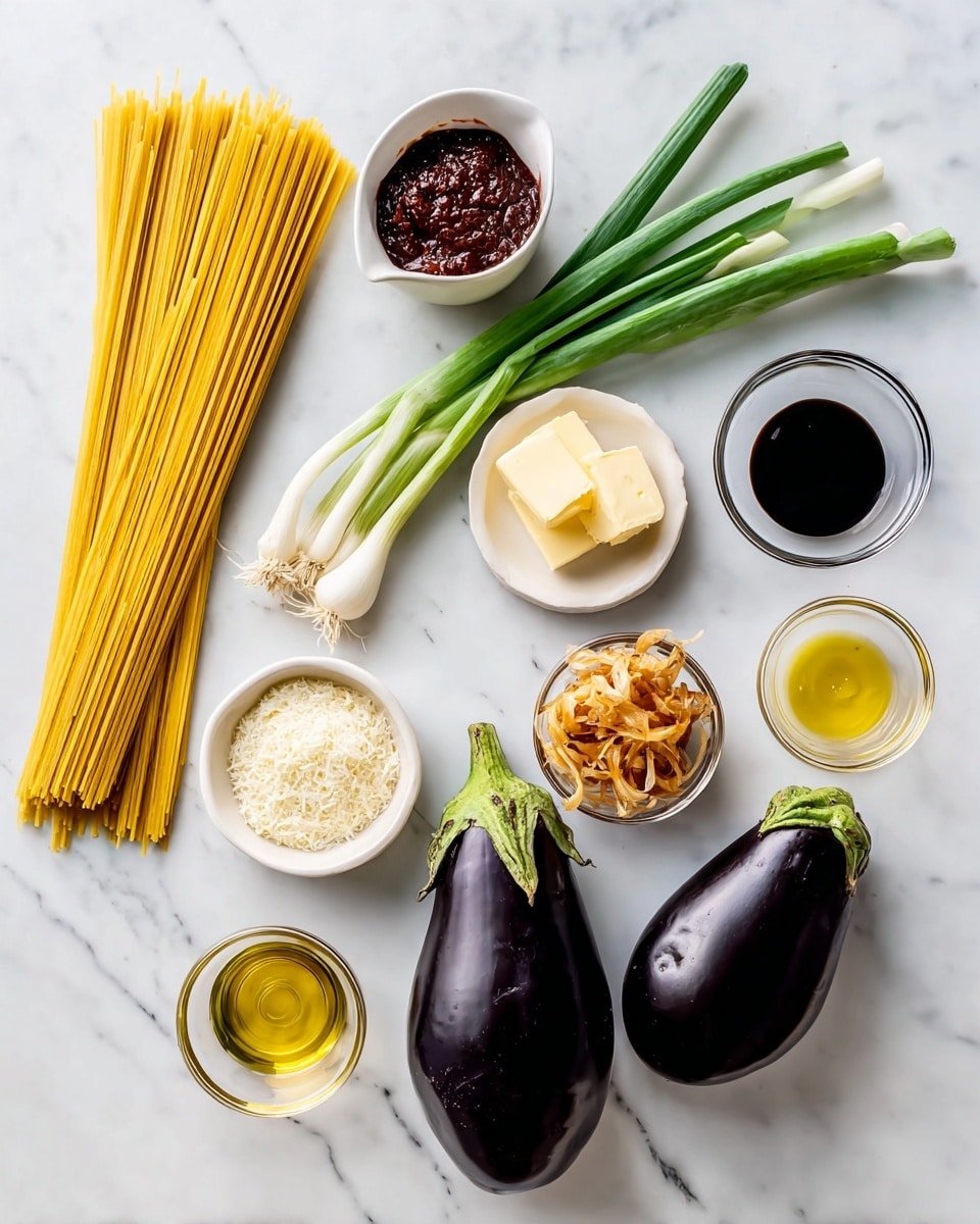 The image shows several ingredients neatly arranged on a white marbled surface. On the left, there is a bundle of long, thin, yellow linguine pasta. Above the linguine is a small white container filled with dark red gochujang paste. Next to it, three green scallions with white roots lay diagonally. To the right of the scallions, a small white plate holds two pale yellow pats of butter. Below that is a small white bowl filled with light beige grated parmesan cheese. Below the parmesan, a small clear bowl has golden brown crispy onions. Toward the right side, two large, smooth, dark purple eggplants with green stems lie close together. Above the eggplants, there are two cloves of light brown garlic. To their right are three small clear bowls: one with dark tamari sauce, one with light yellow grapeseed oil, and one with amber toasted sesame oil. A tiny bowl of white salt is placed near the oils. The setup is clean and bright. Photo taken with an iphone --ar 4:5 --v 7