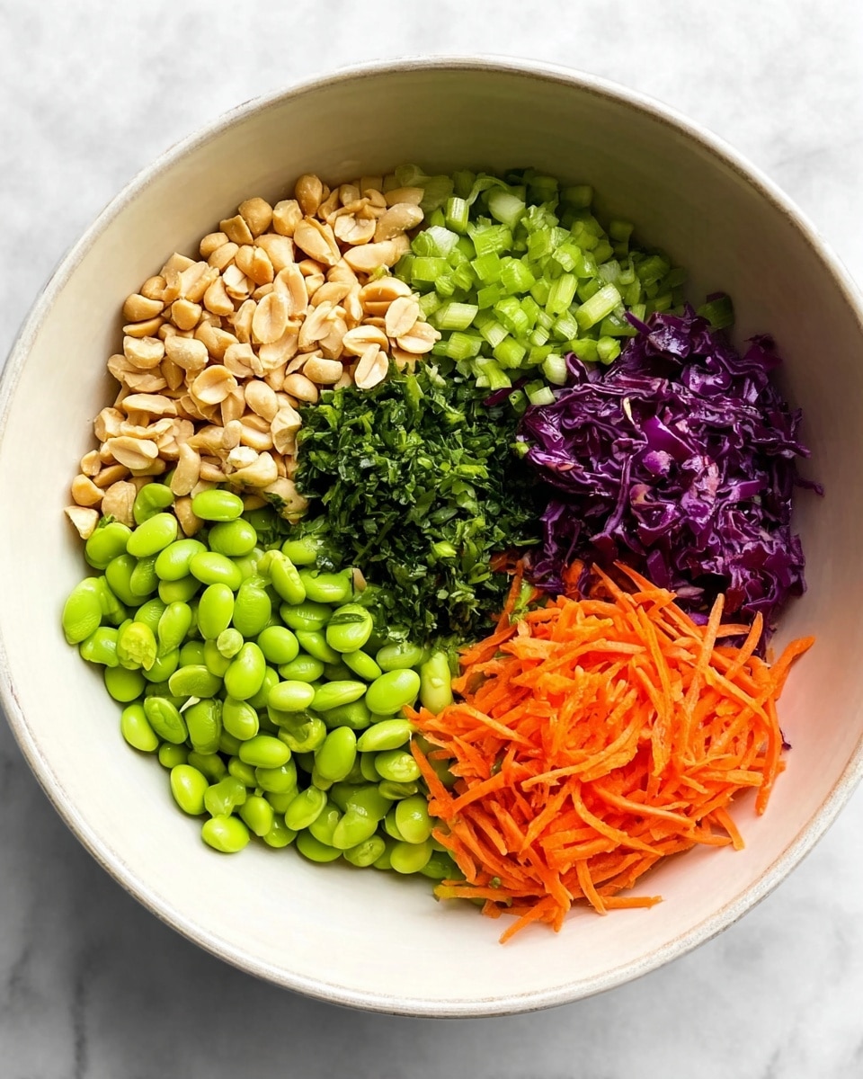 A white bowl on a white marbled surface holds six distinct layers of ingredients. The largest section at the bottom left is filled with bright green edamame beans. Next to it on the bottom right is a pile of thin, shredded orange carrots. Above the carrots, on the right side, there is a small section of finely chopped deep purple cabbage. Next to the cabbage, toward the center, is a portion of light green chopped scallions. To the left of the scallions, there is a heap of roughly chopped fresh green herbs. Above the edamame, near the top left edge, is a cluster of light brown roasted peanuts. The layers are neatly arranged side by side without mixing. Photo taken with an iphone --ar 4:5 --v 7