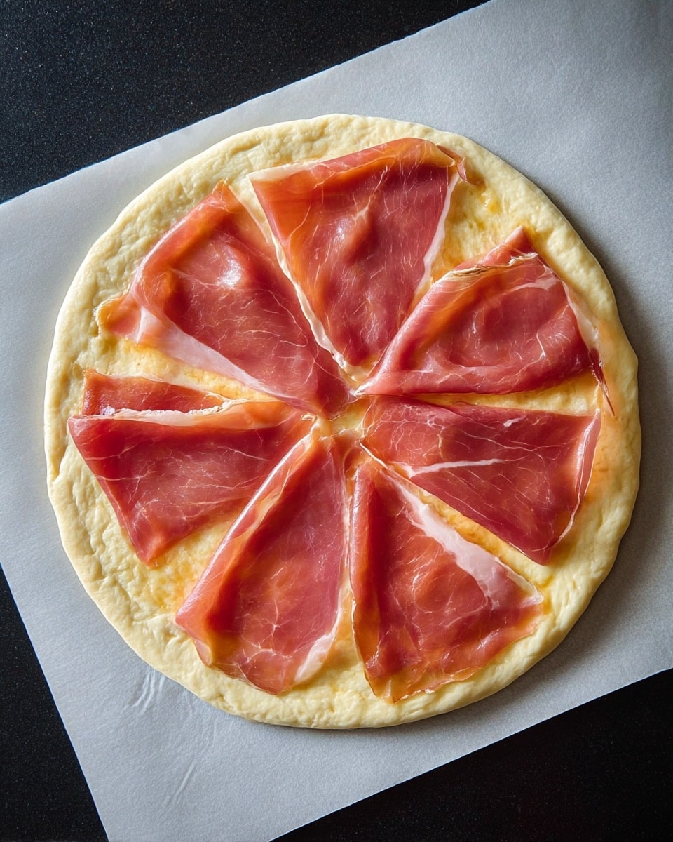 A round pizza dough lies flat on a white parchment paper over a dark surface, forming the base layer. On top, there are eight unevenly placed slices of bright pink and light red cured ham, each slice thin and slightly shiny, covering most of the dough except the edges. The dough has a pale yellow rough texture with some small uneven spots and looks soft. The parchment has light wrinkles around the dough, adding subtle texture. photo taken with an iphone --ar 4:5 --v 7